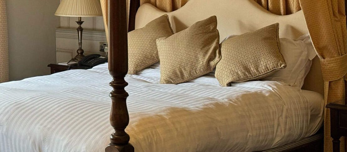 Standard four‑poster room at Tre‑Ysgawen Hall Country House Hotel & Spa featuring a classic four‑poster bed with luxurious drapery and elegant period décor.