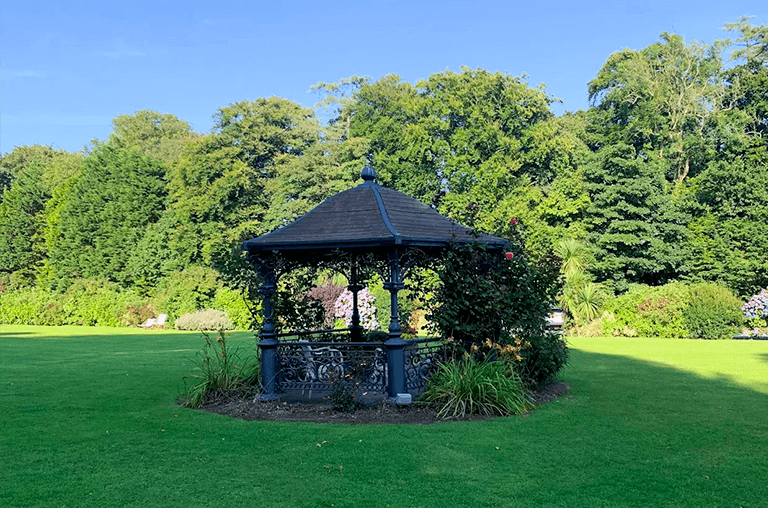 Tre-Ysgawen Hall sculpture garden with elegant artworks surrounded by lush greenery and seasonal blooms.