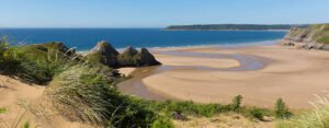 Gower Peninsula coastline with sandy beaches, cliffs, and clear blue sea in South Wales