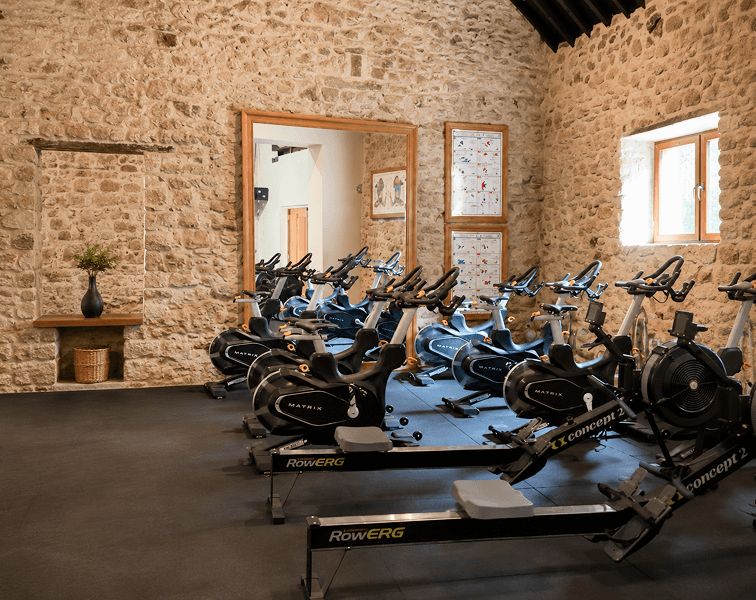 Modern fitness gym at Tre-Ysgawen Hall Hotel & Spa in Anglesey featuring rowing machines, exercise bikes and strength training equipment
